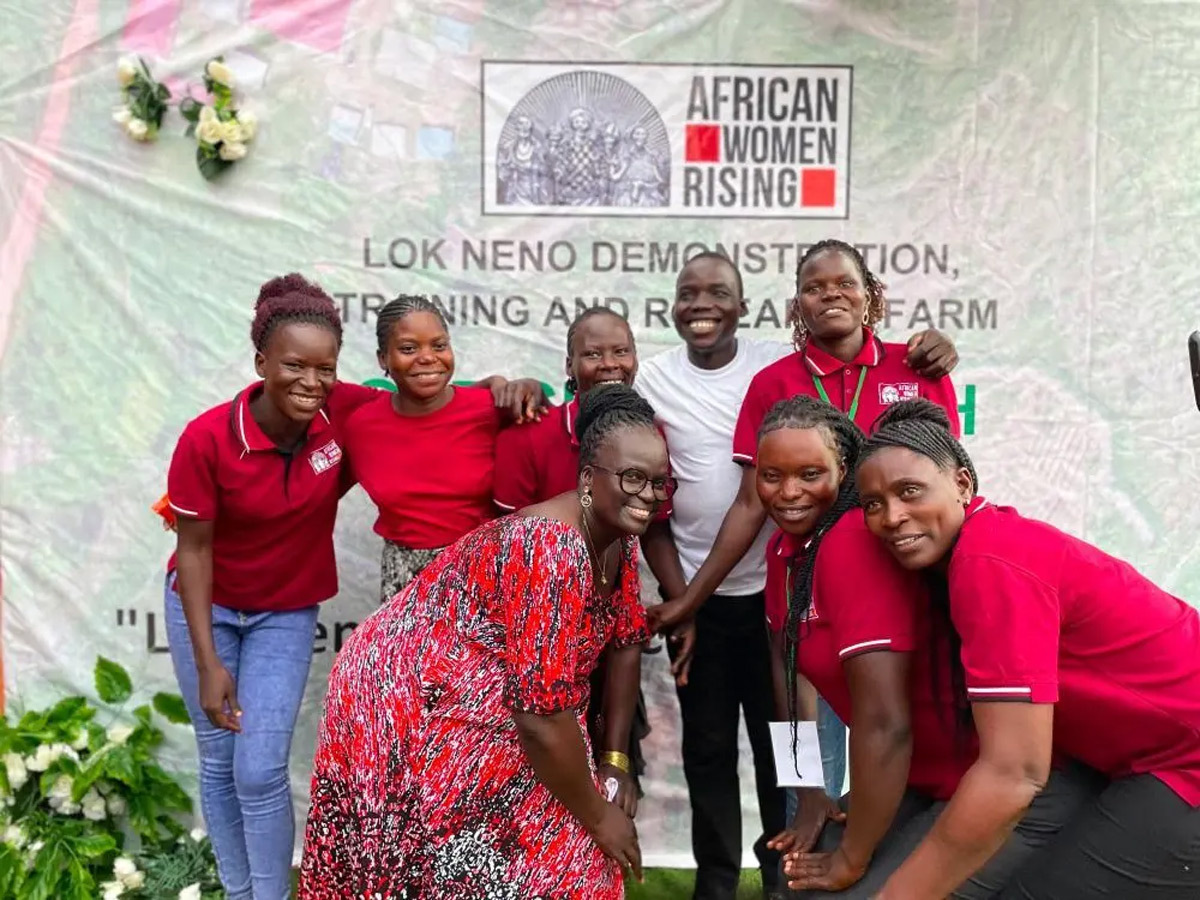 Group smiling in front of a poster that says African Women Rising.