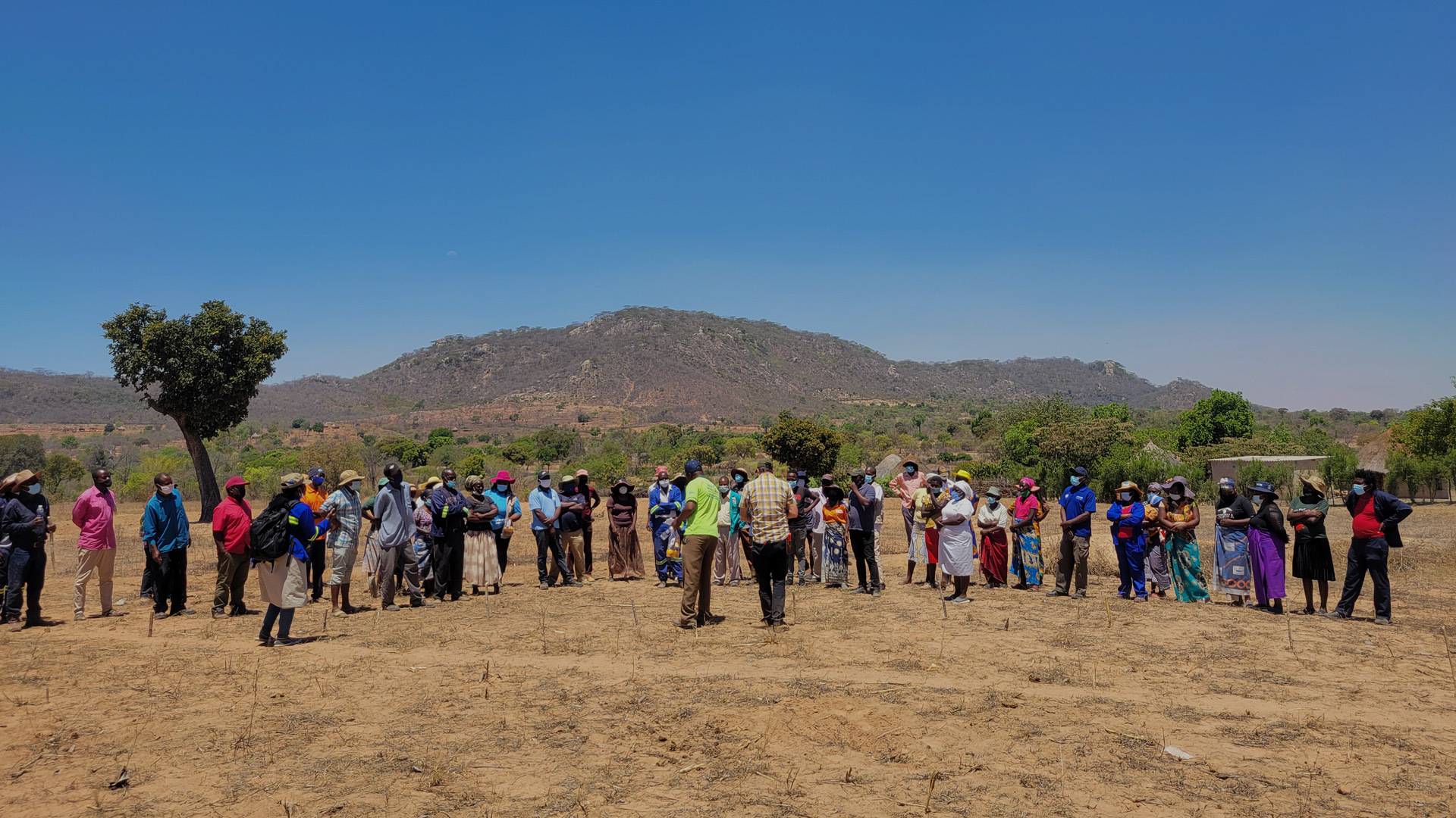Group of people standing in a field in front of a mountain